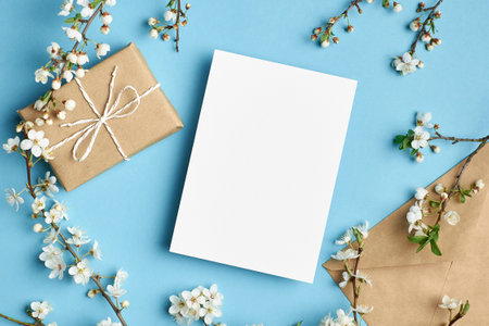 Greeting card mockup with gift box and flowers on blue backgroundの写真素材