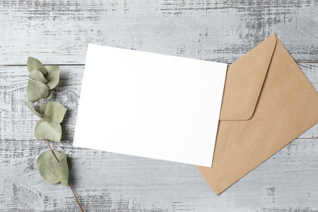 Greeting card mockup with envelope and eucalyptus twig on wooden background