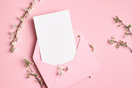 Blank greeting card mockup with envelope and white flowers on pink background