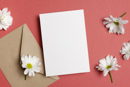 Blank paper greeting card mockup with envelope and white flowers, top view with copy space