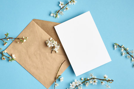 Greeting card mockup with envelope and white cherry flowers on blue backgroundの写真素材