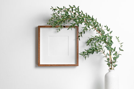 Blank square frame mockup for artwork or print on white wall with eucalyptus plant in vase, frame with copy spaceの写真素材