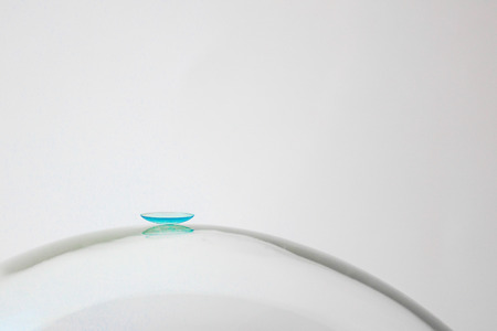 Rigid contact lens on a large glass bowl. Behind the light background. The location of the blue lens is centered.の写真素材