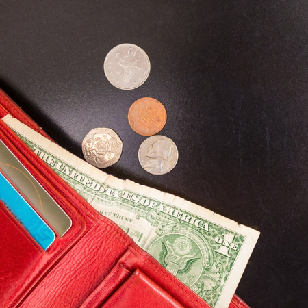 Red wallet with one dollar and small coins on a black background. Payment of expenses, shortage of...