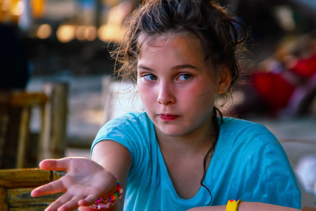 Blond child, girl, at a table in an Asian cafe. On lyiderar emotion, discontent and exactingness. Rest, traveling with children.の写真素材