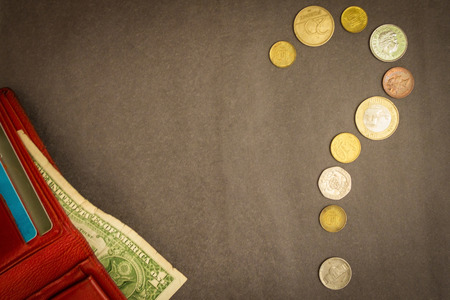 A question mark was drawn from the coins. Financial problems, difficulties. Red purse with one dollar on a gray background.の写真素材