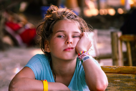 A European-looking girl with a face expressing boredom and anticipation. Asian cafe, travel with children, local cuisine. The background is blurred.の写真素材