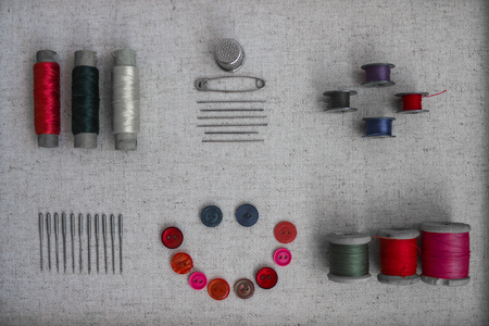 Wooden coils with threads, old buttons for clothes, safety pin, needles, thimble. Tailoring skills, making clothes. View from above.の写真素材