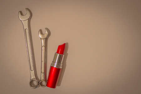 Bright red lipstick and two wrenches. Feminism, women's autonomy. Light background, top view. Vignetting.の写真素材