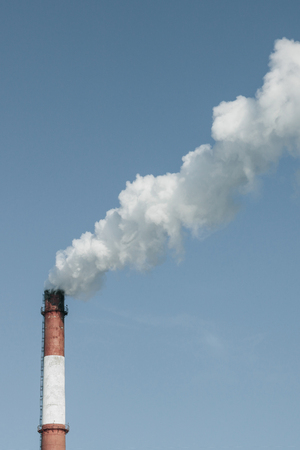 From the industrial pipe goes white thick smoke. Pollution of the environment, harmful emissions...