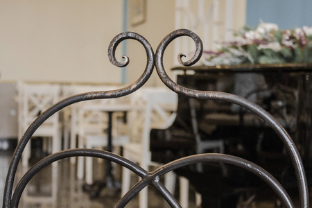 Retro style, old cafe, vintage furnishings. Close-up decorative element of wrought iron, handmade. Muted tone, natural lighting.の写真素材