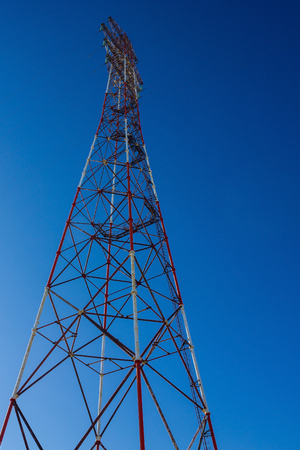 Tower with electric wires. Transmission of electricity, connection to the line. Bright blue sky. Bottom view.の写真素材