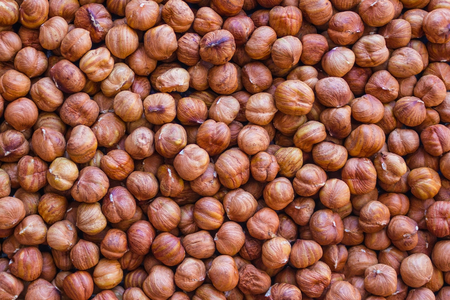 Brown background of large, round hazelnut kernels. Proper nutrition, health care, a healthy...