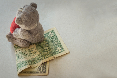 Small cash and a children's toy on a light background. Use of cheap child labor, low pay, lack of funds for a child.A toy of mass production. Vignetting.の写真素材