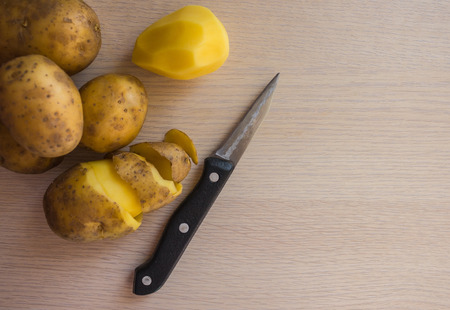 Dishes from potatoes, simple food. On the table there is a large raw potato and a knife. House cooking, vegetarian cuisine.の写真素材