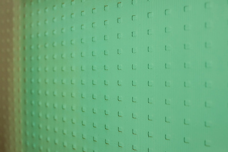 On a light frosted glass, a neutral pattern in a shallow square. Green, turquoise hue. Daylight.の写真素材