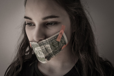 The girl's mouth is sealed with money. How much is silence? Family secrets, skeletons in the closet. Muted tone, vignetting.の写真素材