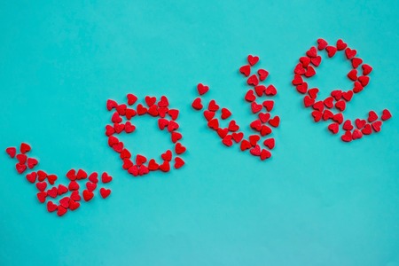 From the little red hearts lies the word love. Recognition, strong feelings, passion. Blue background, daylight.の写真素材