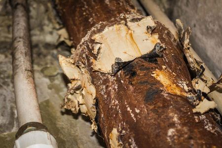 Rusty peeling pipe, on the surface of the remains of the old paint. Corrosion of iron, decomposition, dilapidation. Plumbing works, repair.