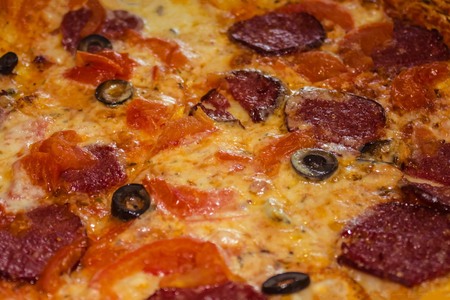 Appetizing Italian pizza, traditional recipe, spicy taste. Ingredients are covered with melted...
