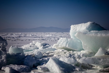 The water is covered with ice, snow. In the foreground are blocks of ice. Arctic, Antarctica, northern region. In the distance the horizon, mountains, blue sky. Vignetting.の写真素材