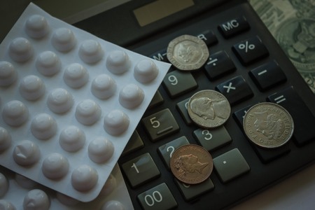 Calculator, small money and pill packaging. Expensive medicine, the cost of treatment. View from above.の写真素材