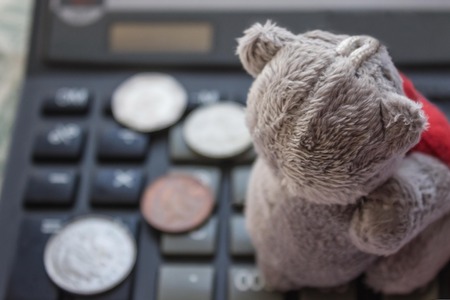 Calculator, small coins and children's toys. High costs for the maintenance of children, rising prices. Gray tones, the background is blurred.の写真素材