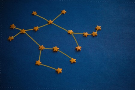 Yellow decorative stars on a blue background, constellation Gemini. Horoscope for born in June. Copy space, drawing made by the author.の写真素材