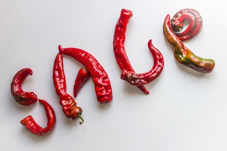 Bright red letters made from hot pepper. Urgent sale, hot offer, discounts. Light background, top view.の写真素材