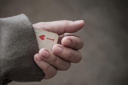 The hand pulls an ace from its sleeve. Concept, symbol. Focus on the playing card. Warm colors,...