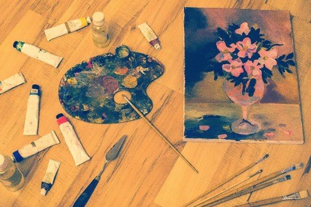 Paints, canvas with the image of colors, palette knives and artistic brushes. Mastery of the artist, talent, fine art. Toning, top view.の写真素材