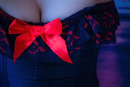 Woman in a corset, open chest, bust. Night, sex, bedding, seduction. Blue toning. The background is...