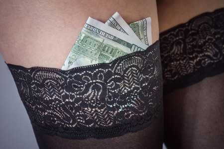 Women's legs in black lace stockings. For gum shoved money, dollars. Sexual services, venality.の写真素材