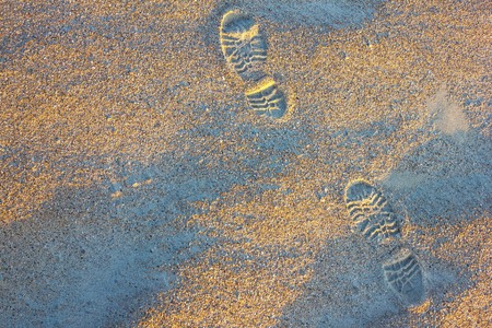 Leaving footprints in the sand. Start a long way, hiking route, your way. Low solar lighting, top view.の写真素材