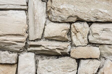 Wall of large raw stones. Different sizes and shapes. Daylight