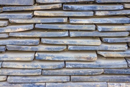 The old tiles are piled in rows. Narrow stripes, staggered. Dirty surface.