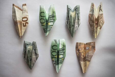 Banknote paper airplanes on a light background. Flight delay, low season, downtime. Financial losses, decline in demand. Vignetting.の写真素材