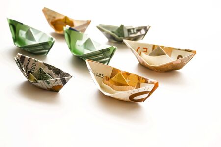 Ships rolled up from banknotes. The cost of cargo transportation, sea cruises. The distant plan is blurred.の写真素材