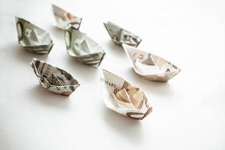 Paper boats made of euro bills. Revenues and expenses of sea carriers. Financial losses of shipowners. Transportation cost. Muted tones, light background.の写真素材