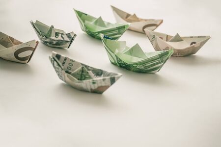 Euros and dollars are wrapped in the form of ships. Rising prices for shipping. Demurrage. Low season. Muted tones.の写真素材