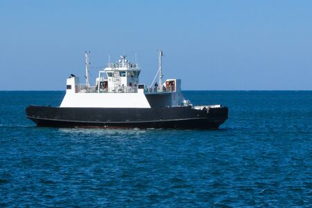The cargo ferry in the blue sea. Clear sky. Transportation of goods and passengers. Side view. Skyline.の写真素材