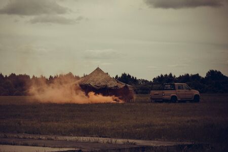 Military camp, base, next to the tent  . Orange fire, smoke. Attack, threat. Away the forest. Muted tones, vignetting.の写真素材