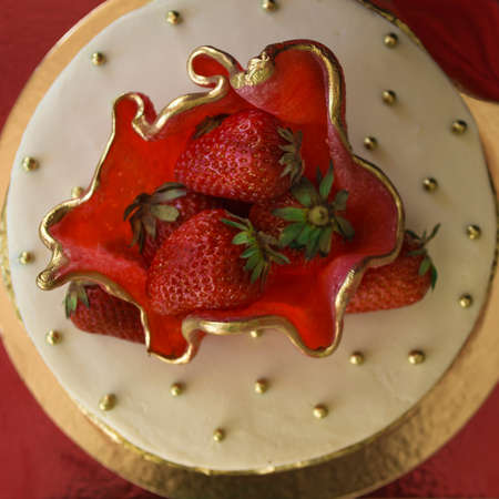Tasty cake on a red background. In the center is a large strawberry, fresh berries. The art of the confectioner. View from above.の写真素材