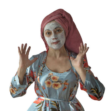 Woman in pajamas, housewife. There is cosmetic cream on the face, and the hair is wrapped in a towel. Silk pajamas, home clothes.の写真素材
