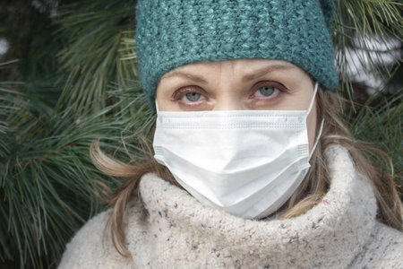 Woman in a white protective mask. Winter, cold season. Covid, epidemic, disease.の写真素材