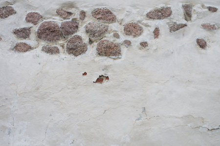 Stone wall, masonry, large cobblestones. Top of it is old white plaster, chips, cracks. Natural texture.の写真素材
