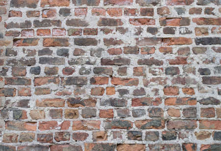 Brick wall, black and orange colors. Old masonry, chips, cracks. White seams.の写真素材