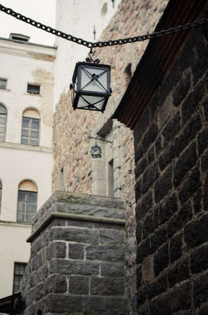 Narrow street of the old town. Rough stone walls. Square lantern on an iron chain. Bottom view.の写真素材