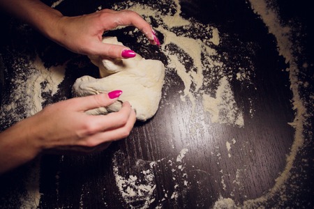 a girl prepares dough for pizza on a black