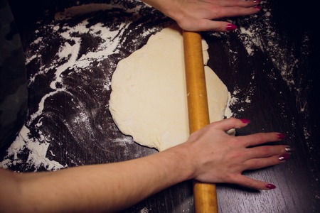 a girl prepares dough for pizza on a black